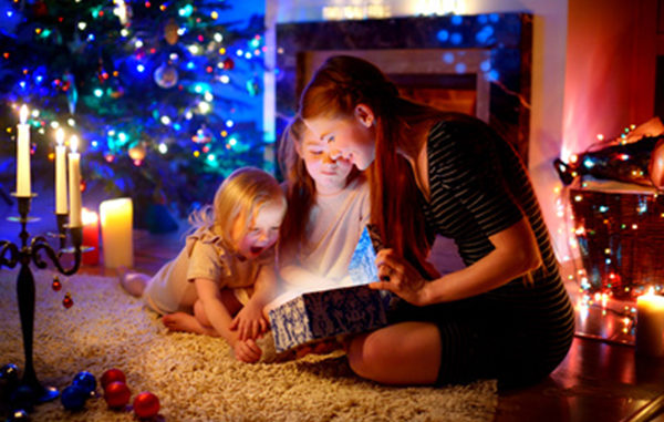 Mother and two little daughters opening a magical Christmas gift